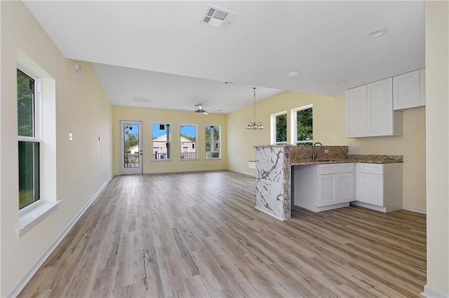 kitchen featuring white cabinets, pendant lighting, light hardwood / wood-style floors, and a healthy amount of sunlight