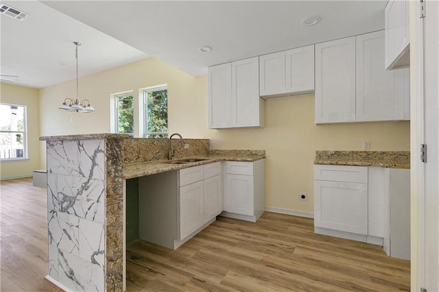 kitchen with white cabinets, decorative light fixtures, light hardwood / wood-style floors, and a wealth of natural light