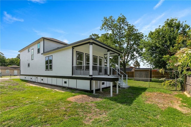 rear view of house with a porch and a yard