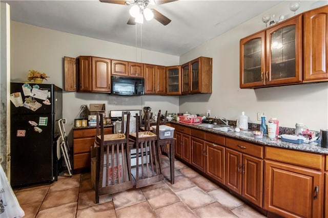 kitchen with black appliances, sink, ceiling fan, dark stone countertops, and light tile patterned flooring