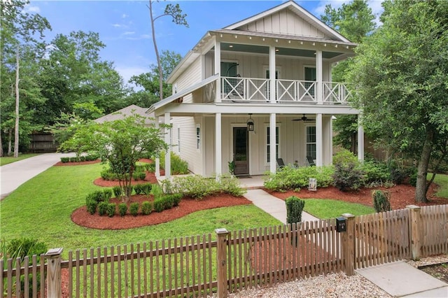 view of front of property featuring ceiling fan, a front lawn, a balcony, and covered porch