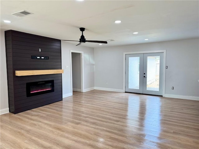 unfurnished living room with french doors, ceiling fan, a fireplace, and light wood-type flooring