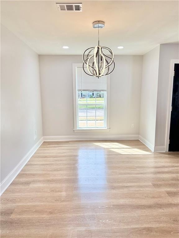 unfurnished dining area featuring an inviting chandelier and light wood-type flooring