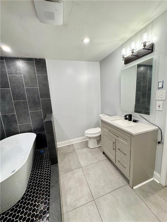 bathroom with tile patterned floors, vanity, toilet, and a washtub