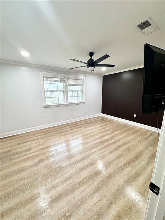 spare room with crown molding, ceiling fan, and light wood-type flooring