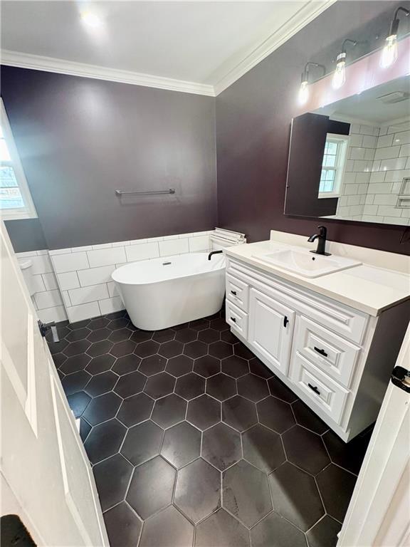 bathroom with a tub, tile walls, tile patterned flooring, ornamental molding, and vanity