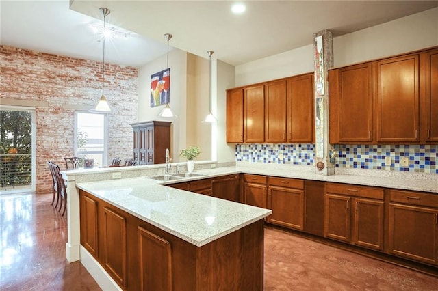 kitchen with backsplash, light stone countertops, sink, and hanging light fixtures