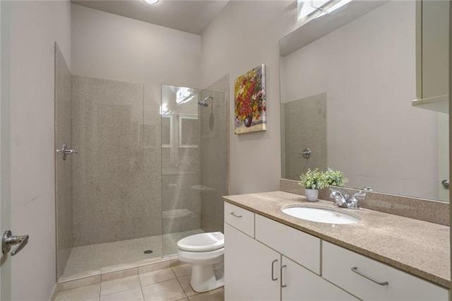 bathroom with toilet, a tile shower, vanity, and tile patterned floors