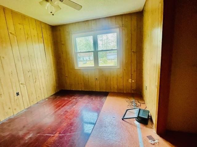 spare room with ceiling fan and wood walls