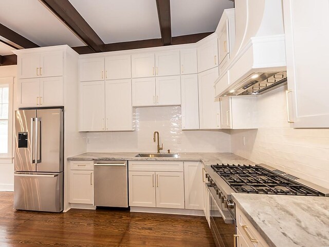 kitchen featuring beam ceiling, appliances with stainless steel finishes, sink, and custom range hood