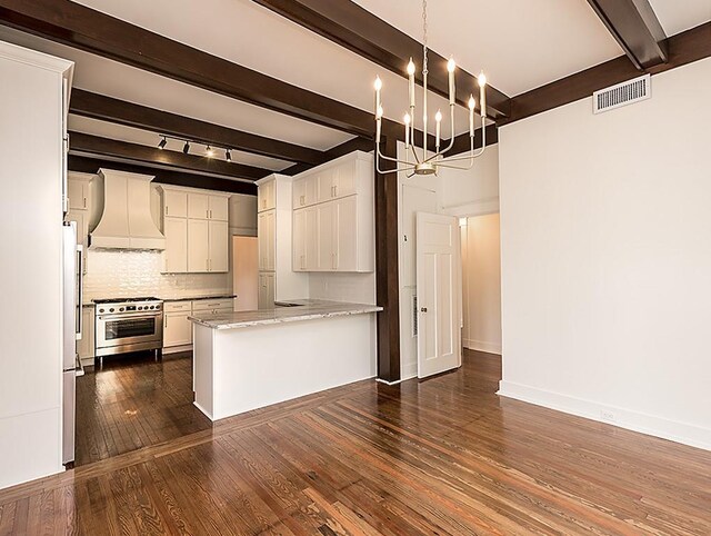 kitchen with tasteful backsplash, stainless steel range, premium range hood, and white cabinetry