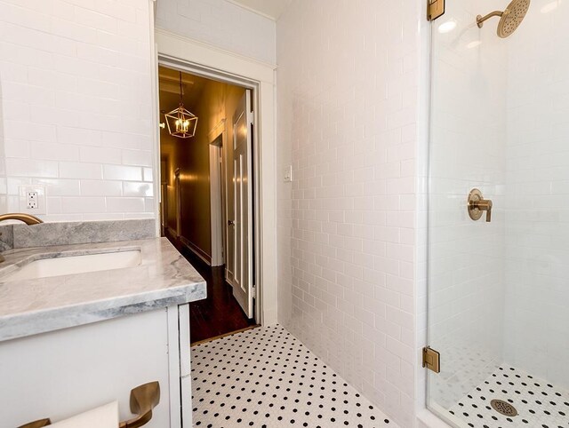 bathroom with a shower with shower door, tile walls, and vanity