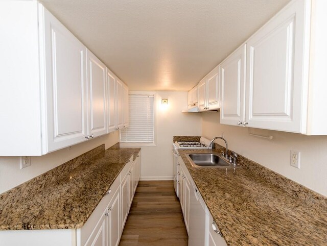 kitchen featuring white cabinetry, white appliances, dark wood-type flooring, dark stone countertops, and sink