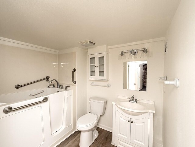 bathroom featuring toilet, a bathing tub, hardwood / wood-style flooring, and vanity