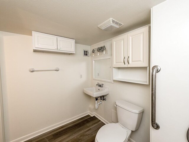 bathroom with toilet, a textured ceiling, and hardwood / wood-style floors