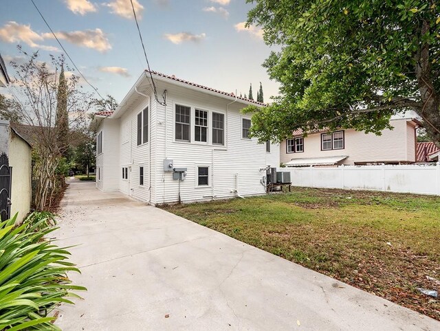 back of property featuring a lawn and central AC