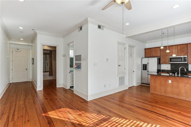 kitchen with ornamental molding, pendant lighting, light hardwood / wood-style floors, and appliances with stainless steel finishes