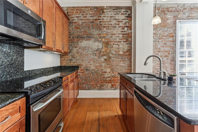 kitchen with pendant lighting, sink, stainless steel appliances, and brick wall