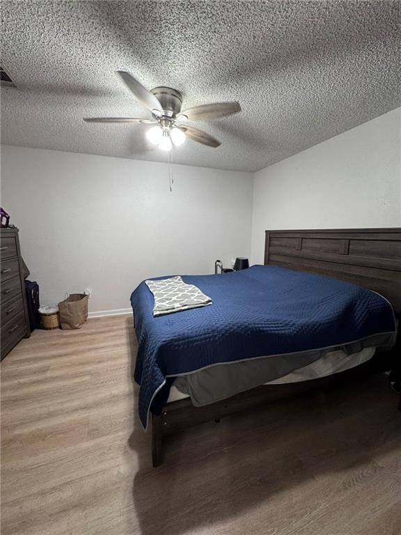 bedroom with ceiling fan, a textured ceiling, and light wood-type flooring