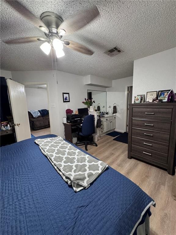 bedroom with ceiling fan, light hardwood / wood-style floors, and a textured ceiling