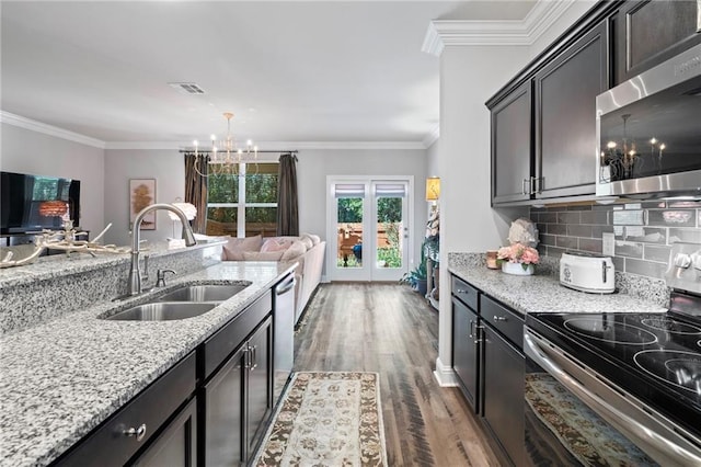 kitchen with appliances with stainless steel finishes, ornamental molding, sink, a notable chandelier, and dark hardwood / wood-style floors