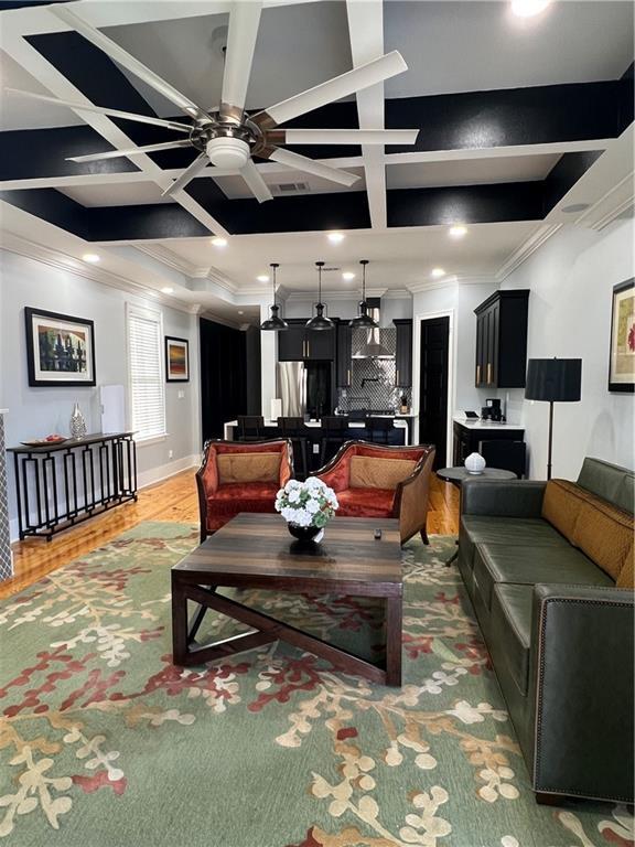 living room featuring crown molding, dark hardwood / wood-style flooring, ceiling fan, and coffered ceiling