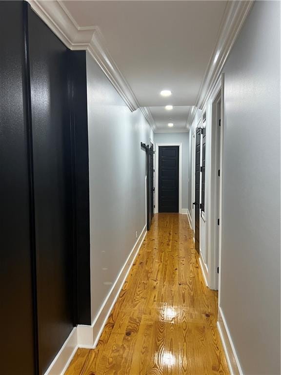 hall with light hardwood / wood-style floors and crown molding