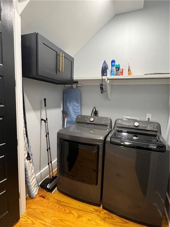 laundry area with separate washer and dryer, cabinets, and light hardwood / wood-style floors