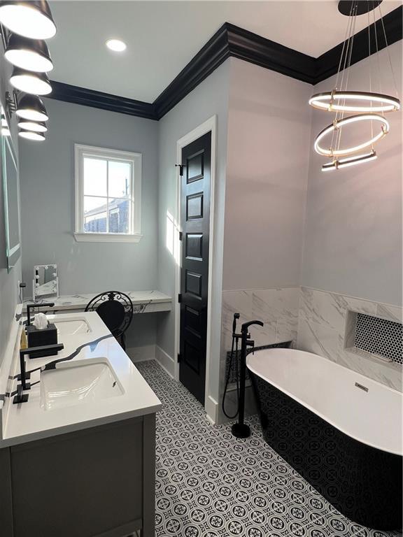 bathroom with a bathtub, crown molding, and vanity