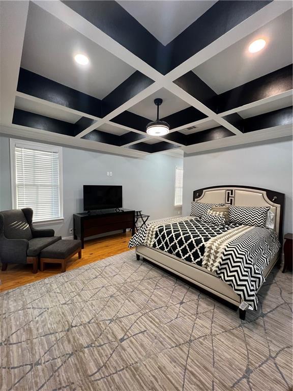 bedroom with hardwood / wood-style floors, ceiling fan, beam ceiling, and coffered ceiling