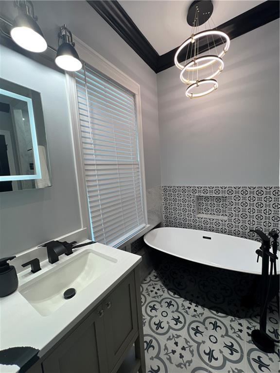 bathroom featuring a tub, vanity, and ornamental molding