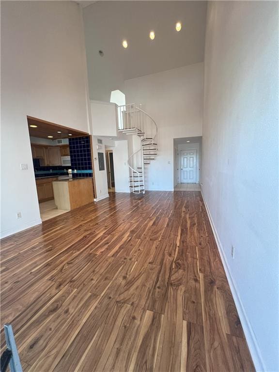 unfurnished living room with a towering ceiling and dark wood-type flooring