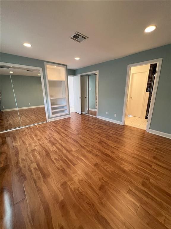 unfurnished bedroom with connected bathroom and hardwood / wood-style floors