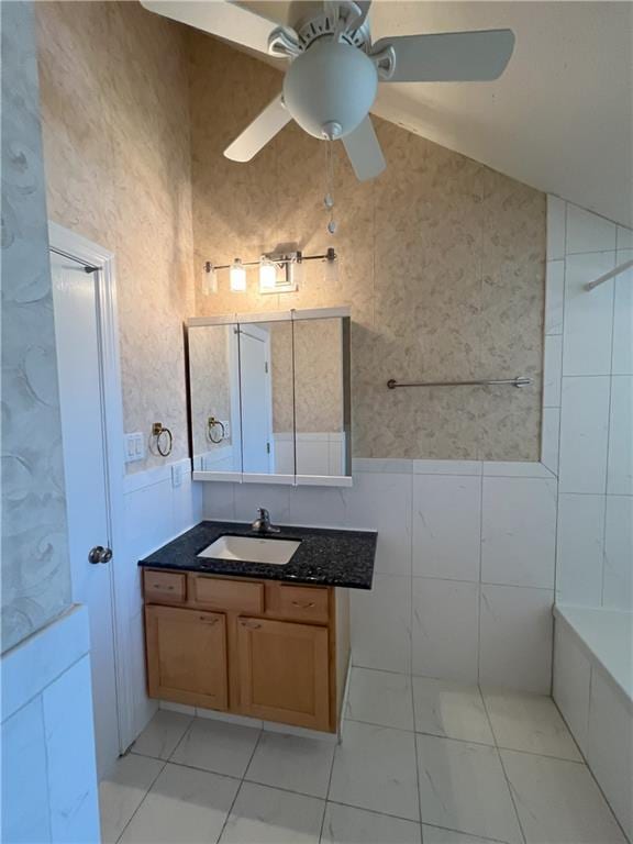 bathroom featuring vaulted ceiling, ceiling fan, vanity, and tile walls