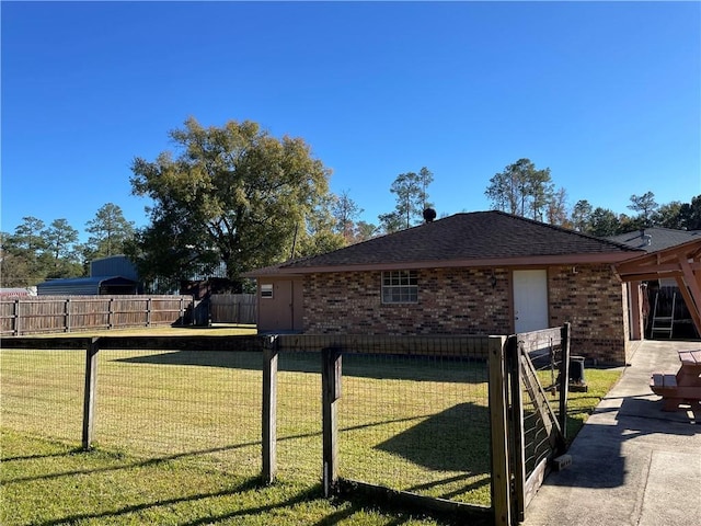 view of side of home with brick siding, a lawn, a shingled roof, and fence