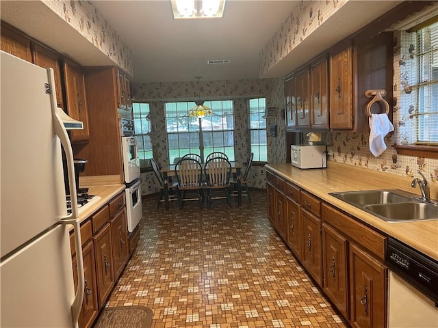 kitchen featuring hanging light fixtures, white appliances, sink, and a wealth of natural light