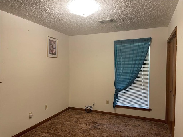 spare room with a textured ceiling and dark colored carpet