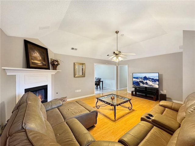 living room with light hardwood / wood-style floors, ceiling fan, and lofted ceiling