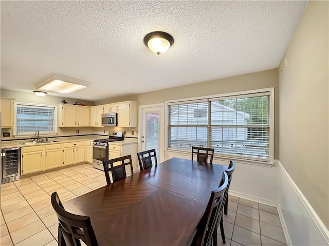 tiled dining space with a textured ceiling, sink, and wine cooler