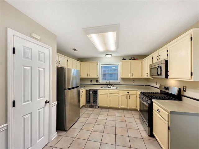 kitchen with sink, light tile patterned flooring, beverage cooler, and appliances with stainless steel finishes