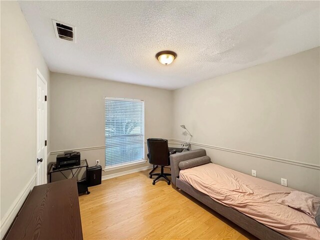 bedroom featuring light hardwood / wood-style flooring and a textured ceiling