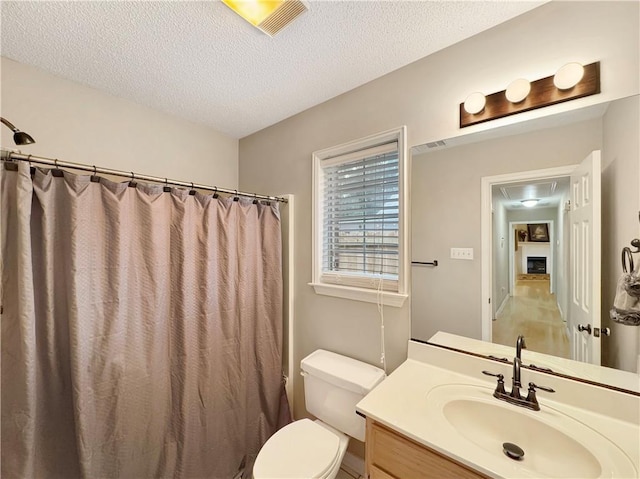 bathroom with a shower with curtain, vanity, toilet, and a textured ceiling