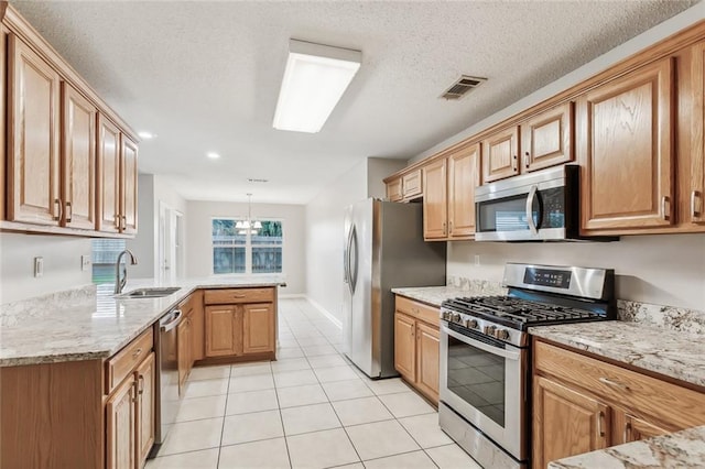 kitchen featuring sink, stainless steel appliances, an inviting chandelier, a textured ceiling, and decorative light fixtures