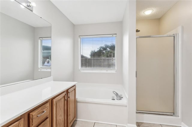 bathroom featuring tile patterned flooring, vanity, plus walk in shower, and a wealth of natural light