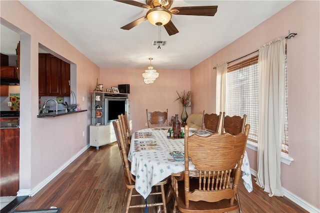 dining room with dark hardwood / wood-style flooring and ceiling fan with notable chandelier