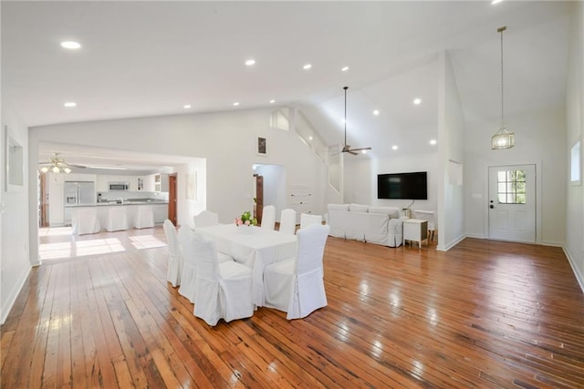 unfurnished dining area with ceiling fan, high vaulted ceiling, and light wood-type flooring