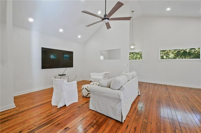 living room with hardwood / wood-style flooring, ceiling fan, and high vaulted ceiling