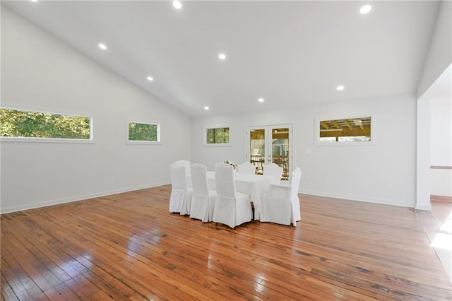 unfurnished dining area featuring vaulted ceiling, light wood-type flooring, and french doors