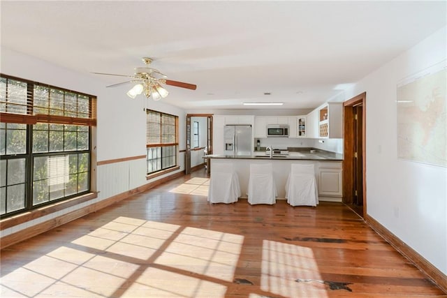 kitchen with appliances with stainless steel finishes, white cabinetry, sink, ceiling fan, and light wood-type flooring