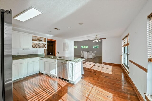 kitchen with kitchen peninsula, white cabinetry, plenty of natural light, and appliances with stainless steel finishes